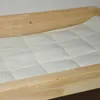 A close-up view of a wooden cat bed with a white quilted mattress. Produktbild-Vorschau