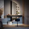 A modern vanity table with a round mirror and integrated lighting, a stool, and decorative items, set in a bedroom. Anteprima dell’immagine prodotto