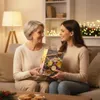Two women sitting on a couch, one giving a gift box to the other. Produktbild-Vorschau