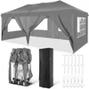 A gray pop-up canopy tent is shown fully assembled, with its sides and windows visible. Below the tent are its folded components, a black carrying bag, and metal stakes with rope loops. Podgląd zdjęcia produktu