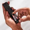 Hands inserting batteries into a remote control. Anteprima dell’immagine prodotto