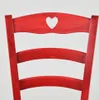 Close-up of the back of a red wooden chair with a heart-shaped cutout in the top. Podgląd zdjęcia produktu