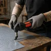 A person wearing gloves is using an electric sheet metal shear to cut a piece of sheet metal on a wooden workbench. Podgląd zdjęcia produktu