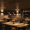 A dining table setting in a restaurant with a modern black pendant light fixture hanging above. Náhled obrázku produktu