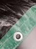 A close-up view of a tarp's edge, showing the reinforced green border and a metal grommet. Produktbild-Vorschau