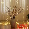 Decorative LED branches in a vase with string lights and a "LOVE" sign in the foreground. Náhled obrázku produktu