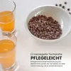 Two glasses of orange juice and a bowl of coffee beans on a white surface, with marketing text overlay. Produktbild-Vorschau