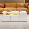 A modern white coffee table with LED lighting is placed in front of a tan leather sofa in a living room setting. Produktbild-Vorschau