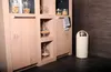A creme colored trash can is shown next to a wooden cabinet with glass jars filled with food items. Voir les images du produit