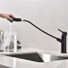 A hand is filling a glass pitcher with water from a black kitchen faucet. Produktbild-Vorschau