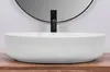 A white vessel sink with a black faucet is shown on a wooden countertop, with a round mirror in the background. Produktbild-Vorschau