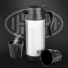 A stainless steel electric travel kettle with a black lid and handle, shown with two black cups, one with steam rising from it. A large, stylized logo is visible in the background. Produktbild-Vorschau