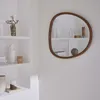 A mirror hangs on a white wall next to shelves with decorative items. Produktbild-Vorschau