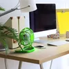 A green desk fan is placed on a wooden desk next to a computer monitor, keyboard, and smartphone. Anteprima dell’immagine prodotto