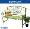 A green metal garden bench with a decorative backrest, a cushion, and a potted plant next to it, set against a white background. Podgląd zdjęcia produktu