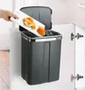 A hand is shown discarding orange peels from a cutting board into a dark gray trash can that is hanging on the inside of a cabinet door. Anteprima dell’immagine prodotto