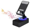 A black smartphone stand with a blue LED light ring, featuring musical notes and sound waves emanating from the base. Produktbild-Vorschau