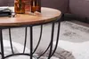 A close-up of a round coffee table with a wooden top and a black metal base, placed on a rug. Voir les images du produit
