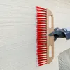 A gloved hand is using a brush to create texture on a white wall. Produktbild-Vorschau
