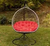 A hanging egg chair with a red cushion sits on a grassy lawn with trees in the background. Produktbild-Vorschau