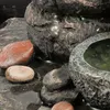 A close-up view of a water feature with stones and water. Produktbild-Vorschau