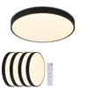 A large, round, black-rimmed LED ceiling light is shown from a top-down perspective. Below it are four smaller, identical ceiling lights stacked, and a white remote control. The lights are illuminated with a warm white glow. Podgląd zdjęcia produktu