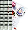 A set of glass jars with black lids, along with a recipe booklet and a packet of gelling agent, arranged on a white surface with some strawberries and a checkered cloth. Anteprima dell’immagine prodotto