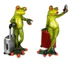 Two decorative frog figurines, one with a suitcase and the other taking a selfie with a suitcase. Produktbild-Vorschau