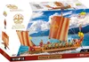 The image shows the packaging of a COBI Roman Warship building block set. The packaging features a dynamic illustration of the assembled model on the water, with mountains and a cloudy sky in the background. Various logos, product details, and branding ele Voir les images du produit