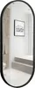 A full-length oval mirror with a black frame, reflecting a bathroom interior with stairs and a framed picture on the wall. Podgląd zdjęcia produktu