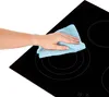 A hand is cleaning a black glass ceramic stovetop with a blue cloth. Produktbild-Vorschau
