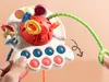A close-up shot of a colorful baby toy with various interactive elements, held by hands. Náhľad obrázku produktu