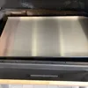 A close-up view of a stainless steel griddle plate inside a grill. Produktbild-Vorschau