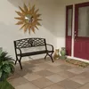 A black metal garden bench sits on a tiled patio in front of a red double door entrance, decorated with a sunburst mirror and garden statues. Anteprima dell’immagine prodotto
