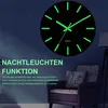 A glowing wall clock is displayed on a dark blue wall, with text describing its features. Produktbild-Vorschau