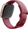 The back of a Fitbit Versa 4 fitness tracker with a raspberry red band and copper rose casing. Podgląd zdjęcia produktu