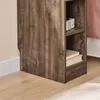 A close-up view of the side of a wooden nightstand with two shelves, one holding a small radio and the other holding two books. Anteprima dell’immagine prodotto
