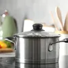A stainless steel pot with a glass lid sits on a stovetop. Podgląd zdjęcia produktu