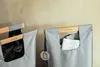 Close-up of two grey fabric recycling bags with wooden handles against a textured wall. Náhľad obrázku produktu