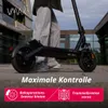 A person stands next to a black electric scooter on a paved surface, with a modern building in the background. Produktbild-Vorschau