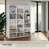 A white bookshelf filled with CDs, DVDs, and books, next to a potted plant and large windows with curtains. Náhled obrázku produktu