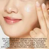A close-up of a person applying cream to their face. Produktbild-Vorschau