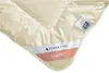A close-up view of a cream-colored duvet or comforter, showing its stitching and labels. Voir les images du produit