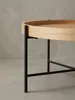 Nahaufnahme eines Details des Couchtischs: die saubere Verbindung zwischen dem schwarzen Metallbein und der Unterseite der runden Tischplatte aus Eichenholz._#sku_BARWL6.493# Produktbild-Vorschau
