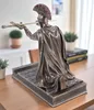 A bronze-colored statue of a Roman centurion kneeling on a base, holding a sword. The statue is placed on a wooden table in a room with a blurred background. Produktbild-Vorschau