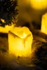 A close-up of a battery-operated LED candle with a flickering flame, surrounded by wispy material and what appears to be a pine branch. Náhľad obrázku produktu