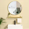 A bathroom vanity with a round gold mirror above a sink and shelf. Produktbild-Vorschau