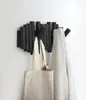 A black wall-mounted coat rack with multiple pegs, holding a beige tote bag and a textured blanket. Anteprima dell’immagine prodotto
