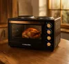 A mini oven with a roasted chicken inside, placed on a wooden table. Produktbild-Vorschau