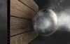 A wrecking ball is about to hit a wooden-like wall. Produktbild-Vorschau